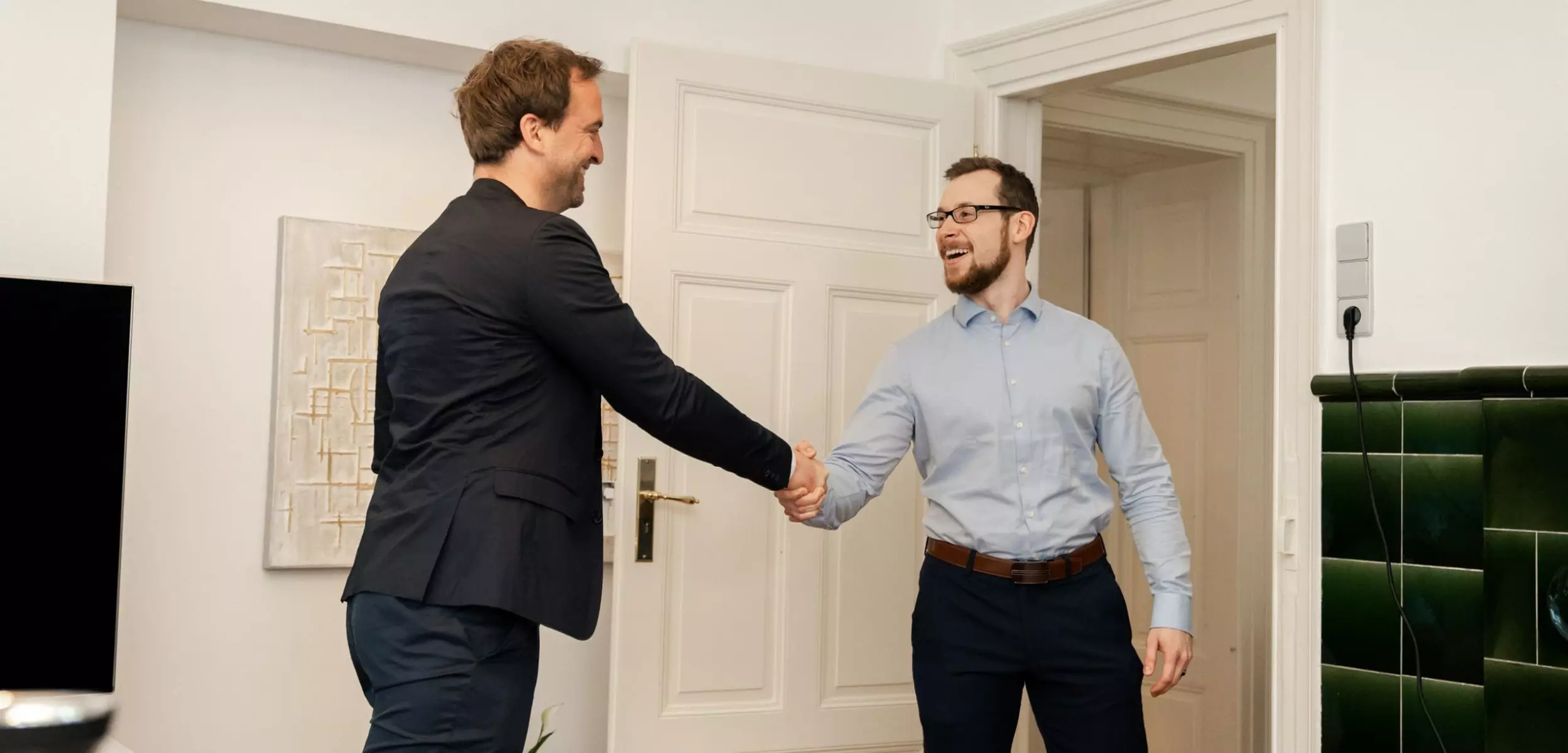 Zwei Männer geben sich erfreut die Hand im Büro